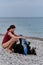 Bernese Mountain Dog lies and rests while girl gives him massage with beach towel. Dog traveler enjoy vacation. Caucasian woman