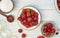 Berries in a bowl and colander, glass jars and sugar on a white wooden table