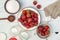 Berries in a bowl and colander, glass jars and sugar on a white wooden table