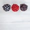 Berries platter with fresh organic red cowberry, blueberry and blackberry wooden table, top view