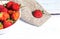 Berries of ripe strawberries lie in a white high plate, which stands on a light wooden background on a napkin made of burlap.