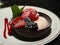 Berries with sorbet in chocolate shell on white dish with raspberry syrup.