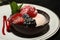 Berries with sorbet in chocolate shell on white dish with raspberry syrup.