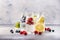 Berry and citrus soft drinks and cocktails in glass bottles on gray stone table background, copy space