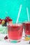 Berry compote. Fruit vitamin drink in glass and ripe fresh berries on a bright background