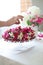 Berry Fruit cake, homemade biscuit cake with cream, in woman hands against of light summer flowers background