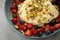 Berry fruit salad with strawberries, blueberries, raspberry, pistachio, lemon zest and linseed oil quark cream in blue bowl for