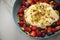 Berry fruit salad with strawberries, blueberries, raspberry, pistachio, lemon zest and linseed oil quark cream in blue bowl for