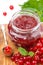 Berry jam in a glass jar and fresh red currants on wooden board