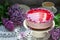 A berry mousse cake with chocolate base and juice jelly, decorated with lilac flowers, served with coffee.