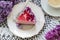 A berry mousse cake with chocolate base and juice jelly, decorated with lilac flowers, served with coffee