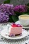 A berry mousse cake with chocolate base and juice jelly, decorated with lilac flowers, served with coffee