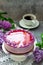 A berry mousse cake with chocolate base and juice jelly, decorated with lilac flowers, served with coffee