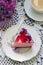 A berry mousse cake with chocolate base and juice jelly, decorated with lilac flowers, served with coffee