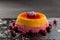 Berry orange pudding on stone plate with cranberry on black background