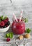 Berry smoothie in a glass jar and berries in a white bowl