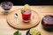 Berry tea in a cup next to a teapot spoon and lemon and lemon balm on a round stand top view.