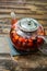 Berry tea in a glass teapot on a wooden table.