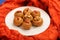 Besan laddu, handmade vegan sweets with wallnuts and goji berries on orange ethnic cloth