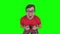 Bespectacled man makes faces playing on game console. Green screen