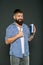 The best care ever. Bearded man showing thumbs up for hair care product on grey background. Happy hipster liking his