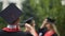 Best friends graduates posing for camera, throwing graduation caps into the air