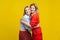 Best friends hugging. Portrait of two charming women in stylish casual clothes, isolated on yellow background