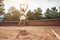 She is the best! Full length of beautiful young woman in sports clothing standing on tennis court. Sporty attractive woman holding