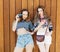 The best lifestyle portrait of two best friends girls wearing stylish bright outfits, denim shorts and vintage camera. On