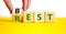 Best rest symbol. Businessman turns wooden cubes and changes the word Rest to Best. Beautiful yellow table white background.