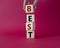 Best symbol. Concept word Best on wooden cubes. Businessman hand. Beautiful red background. Business and Best concept. Copy space