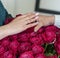 Betrothal ring on woman hand with pink bouqet of roses. Romantic event