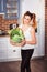 Beuatiful smiling girl holding basket of fresh vegetables on modern scandinavian style kitchen background