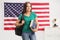 Beutiful female student with a backpack and books posing in front of USA flag