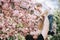 Beutifull little boy in his father hands is holding a cherry blossom branch and smiles