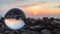 Beutifull sunset reflection inside crystal ball on stones, sun over water, beach, landscape