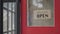 A beverage restaurant worker flips a glass entry door sign from closed to open. Start your work day of a small business greenhouse