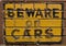 Beware of Cars sign on a brick wall