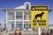 A Beware of Dog Sign in front of a seaside mansion. Warning to visitors or burglars. Security and protection in a residential home