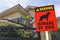 A Beware of Dog Sign in front of a typical 2 story house. Warning to visitors or burglars. Security and protection in a