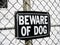 A beware of dog sign on a mesh fence as a safeguard warning of dangerous rottweiler attack if trespassing