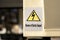 Beware of electric hazard sticker warning label on a generic industrial factory production line machine. Electricity, high voltage