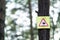 Beware of Ticks warning sign on a tree in the forest against a blurred background