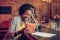 Bewitching Afro-American woman watching funny video on tablet at bar