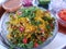 Bhel chaat in a plate with onion,tomato, pomegranate, tamarind water and mint water as a background