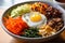 Bibimbap bowl with an array of colorful vegetables and a perfectly fried egg on top, ready to be mixed and savored