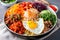 Bibimbap bowl with an array of colorful vegetables and a perfectly fried egg on top, ready to be mixed and savored