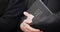 Bible, funeral and hands closeup of a priest for religion, sad and mourning event in church. Faith, male person and