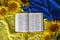 Bible Holy Writ and sunflowers on background of flag Ukraine