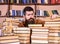 Bibliophile concept. Teacher or student with beard sits at table with books, defocused. Man on hopeful face between